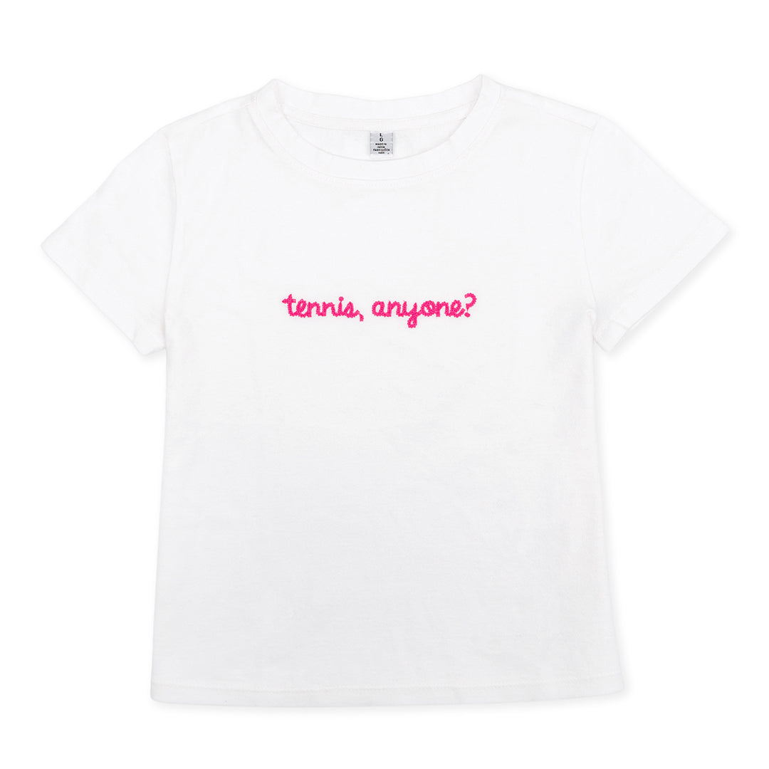 White t shirt lays flat on a white background. The front is embroidered with the words "tennis anyone" in hot pink cursive font