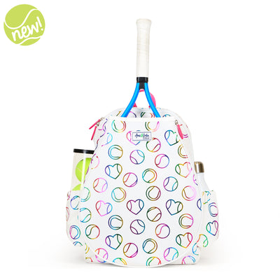 White kids tennis backpack with hot pink zippers and metallic rainbow tennis balls and hearts printed on the fabric.