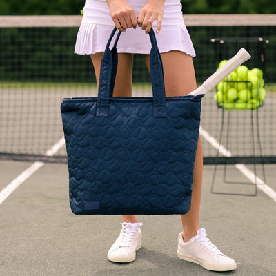 Navy nylon tennis tote with tennis ball quilted pattern.